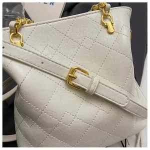Detail of quilted leather texture and gold chain handle on off-white bucket bag