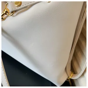 Detailopname van witte lederen tas met litchi-patroon en luxe goudkleurige metalen gespen