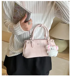 Detail of pink faux leather bucket bag with fashion metal tag and plush charm