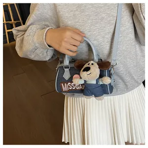 Close-up of denim Boston bag with plush dog charm and Missgai embroidery detail