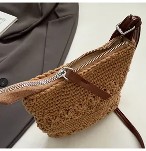 Détail d'un sac à bandoulière en paille tissée avec fermeture éclair et tirette en cuir