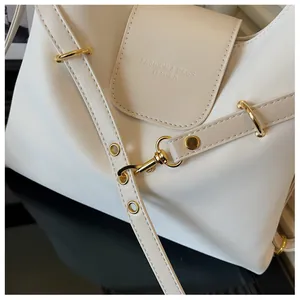 Detailopname van de crèmewitte leren tas met gouden metalen gespen en modieuze reliëf