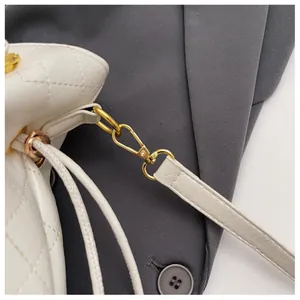 Macro detail of white quilted leather bucket bag featuring gold metal hardware and stitching
