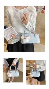 Detail of light blue faux leather bucket bag with cute plush puppy charm and metal tag