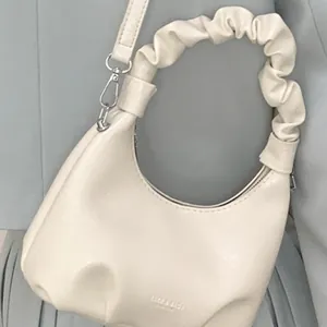 Chic pleated crescent shoulder bag in creamy white PU leather with bow-style handle