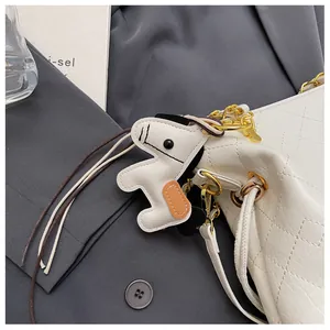 Detail of white quilted leather bucket bag with gold chain and horse charm accent