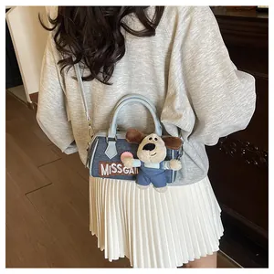 Detail shot of denim Boston bag featuring Missgai embroidery and a cute puppy plush charm