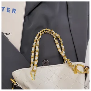 Detailed close-up of quilted chain handle on a white faux leather bucket bag