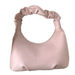 Pink crescent shoulder bag with scrunchie handle and pleated vegan leather finish