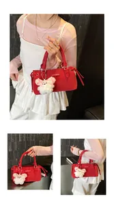 Close-up of red canvas handbag with fashion metal logo and plush bear keychain detail