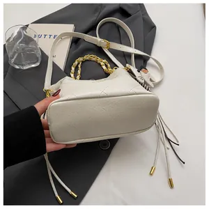Detail of beige quilted bucket bag with golden chain handle and cute puppy charm