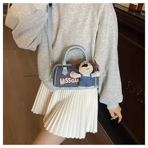 Close-up of blue denim Boston bag with Miss Gail embroidery and cute plush dog charm