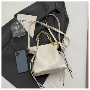 Detail of white quilted bucket bag with gold chain handles and cute horse charm on top