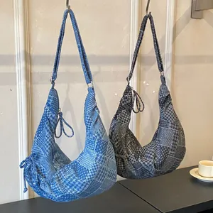 Denim patchwork crescent shoulder bag in light blue and dark grey with zip closure