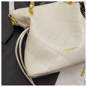 Close-up of white quilted leather bucket bag with gold chain and drawstring detail