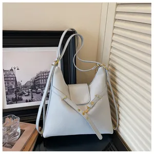 Detail van lichtblauwe tas van oliewasleer met logo-opdruk en goudkleurige metalen delen