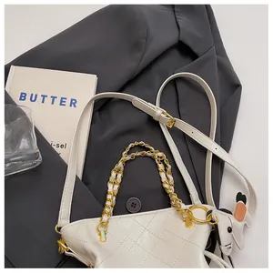 Close-up of white quilted bucket bag with gold chain and cartoon puppy charm detail