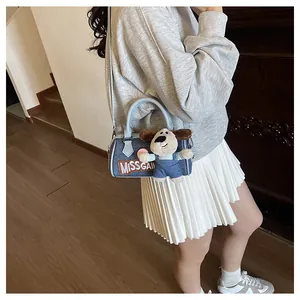 Detail of blue denim Boston bag with dog plush charm and MISSGAI embroidery logo