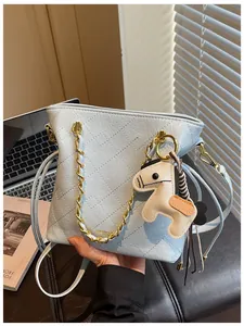 Close-up of light blue quilted leather bucket bag with gold chain and horse charm