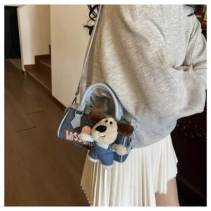 Detail of light blue denim Boston bag with MISS embroidery and cute puppy plush charm