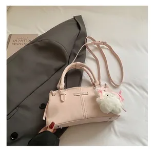 Detail of pink crossbody bag with a plush bunny charm on a professional office setting