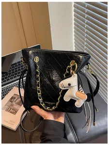 Detail of black quilted leather bucket bag with gold chain and white pony charm accessory