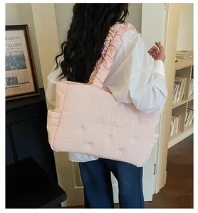 Close-up of light pink quilted nylon tote bag featuring white embroidery and bow details