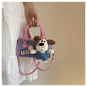 Detail of blue denim Boston bag featuring pink leather trim and a cute puppy plush charm