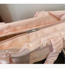 Close-up of a smooth metal zipper on a pink quilted nylon tote bag with fine stitching