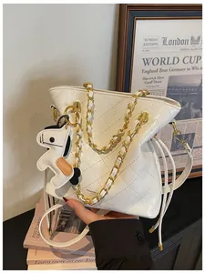Detail of white quilted bucket bag featuring a gold chain strap and a horse charm