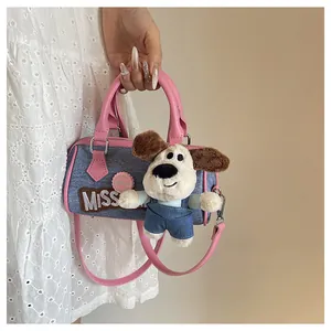 Detail of blue denim Boston bag featuring pink leather handles and cartoon dog charm