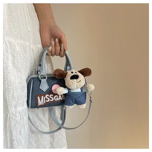 Blue denim Boston bag with white embroidery and cute puppy charm held by model