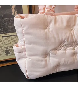 Close-up of pink quilted nylon tote featuring bow embroidery and ruched handle detail