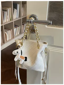 Detail of quilted leather bucket bag with gold chain strap and cute horse charm