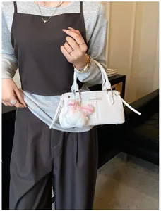 Close-up of white leather bucket bag featuring a fashion tag and plush charm detail