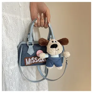 Detail of blue denim Boston bag with plush dog charm and white MISSGAIL embroidery