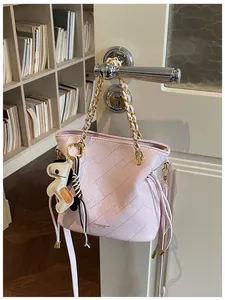 Close-up of pink quilted bucket bag with gold chain handle and horse charm on a door
