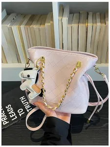 Detail of pink quilted bucket bag with gold chain and cartoon puppy charm decoration