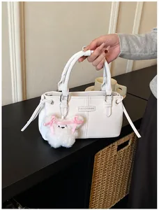 Detail of white PU bucket bag featuring a cute plush puppy charm and fashion label