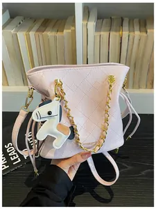 Pink quilted bucket bag with golden chain and horse pendant on a bookshelf background