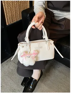 Detail of white leather handbag with plush bear charm and Fashion & Bags leather patch