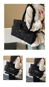 Detail of black quilted nylon tote featuring white bow embroidery and ruffled strap