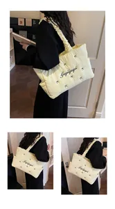 Detail view of yellow quilted tote bag with ruffles and Gugiigugii embroidery