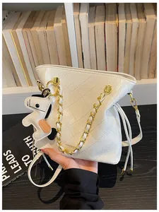 Close-up of a white quilted bucket bag with gold chain handle and cartoon horse pendant