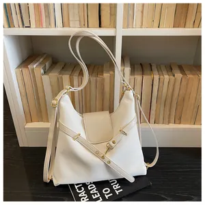 Detail van witte gewaxte leren tote bag met verstelbare riemen en goudkleurige hardware