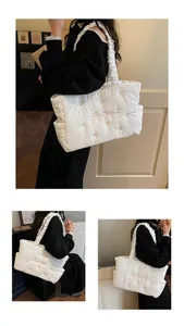Close-up of white quilted tote bag with embroidered text and ruched cloud shoulder strap