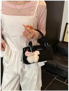 Close-up of black bucket bag with plush bear charm and fashion logo plaque