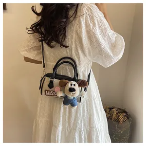 Detail of canvas Boston bag with black leather trim, Miss patch, and plush charm