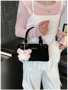 Detail of black suede tote bag featuring a cute white teddy bear charm and fashion logo