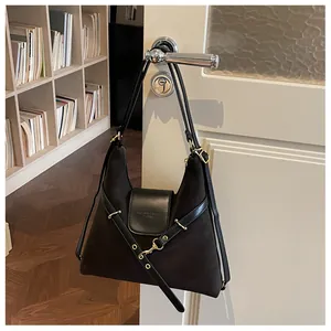 Detail van een zwarte hobo-tas van oliewasleer die aan een deurklink hangt